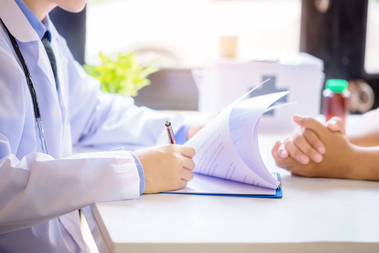 doctor man consulting patient while filling up application form desk hospital