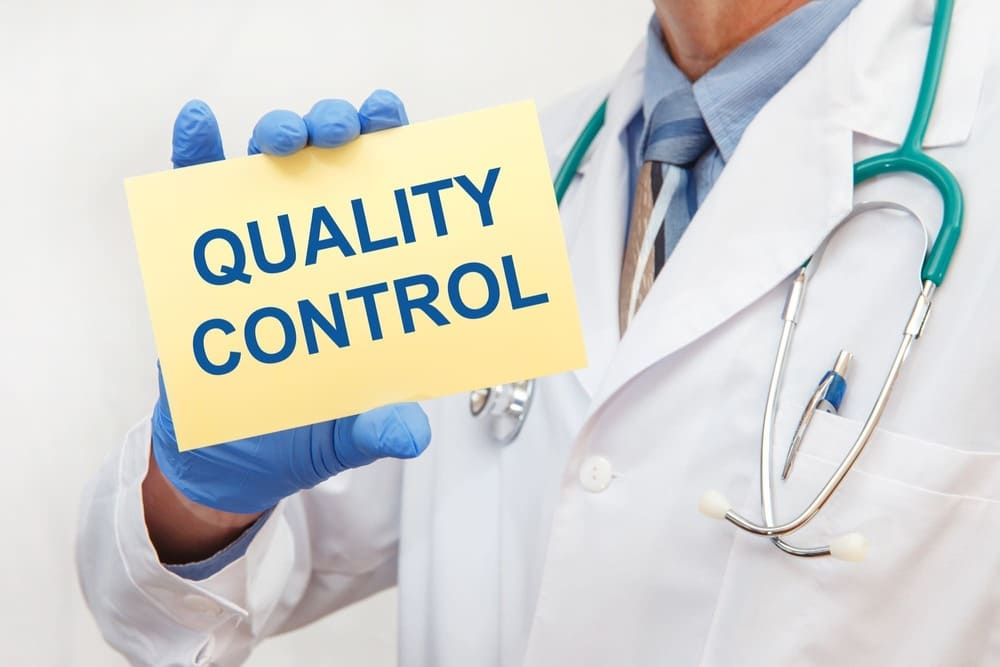 close up male doctor gloves holding sign with text quality control